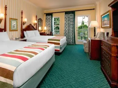 a hotel room with two beds and a desk at Disney's Boardwalk Inn in Orlando