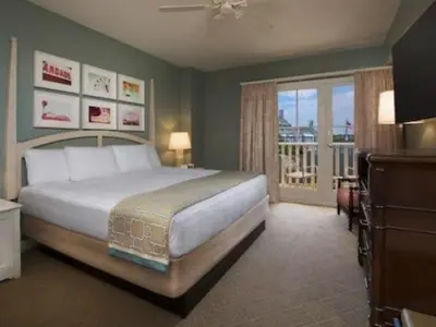 a bedroom with a large bed and a balcony at Disney's Boardwalk Inn in Orlando