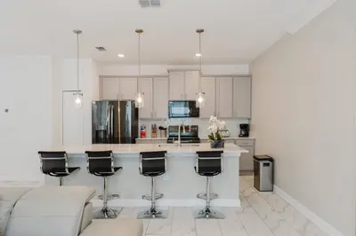 a kitchen with white cabinets and a bar with stools at 3017 SL new 11 guests heat pool BBQ near Disney in Kissimmee