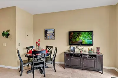a dining room with a table and a television on a wall at 2541 - Casa 3 Quartos/3 Banheiros | Piscina Privativa & Resort in Orlando