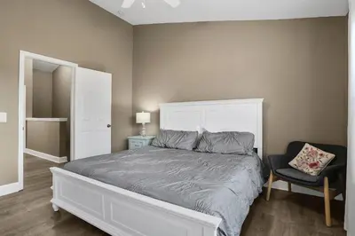 a bedroom with a white bed and a chair at Casa 3Q Windsor Hills, Piscina + Perto da Disney in Orlando