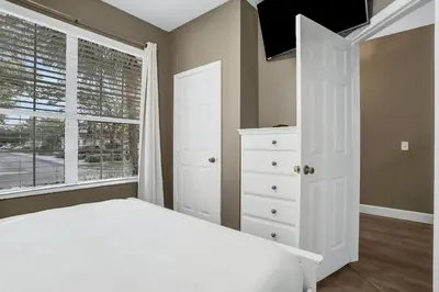 a bedroom with a white bed and a window at Casa 3Q Windsor Hills, Piscina + Perto da Disney in Orlando