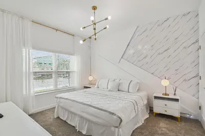 a white bedroom with a bed and a window at Luxuosa Casa 4Q/3B Storey Lake in Kissimmee