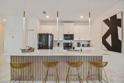 a kitchen with white cabinets and a counter with bar stools at Luxuosa Casa 4Q/3B Storey Lake in Kissimmee