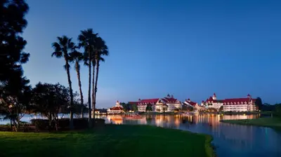 a resort with palm trees and a lake at night at Disney's Grand Floridian Resort And Spa in Orlando
