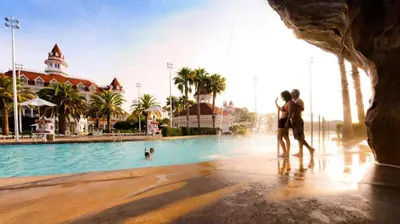 a couple kissing in front of a pool at a resort at Disney's Grand Floridian Resort And Spa in Orlando