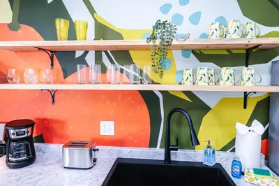 a kitchen counter with a sink and a colorful wall at StylishAptWtrGrdnOppLake&Prk&Yrd in Orlando