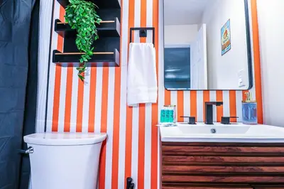 an orange and white bathroom with a sink and a mirror at StylishAptWtrGrdnOppLake&Prk&Yrd in Orlando