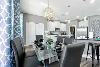a dining room and kitchen with a glass table and chairs at Waterfront Villa showcasing a theater, games room, and a private pool in Kissimmee