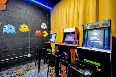 a room with two arcade games in front of a curtain at Waterfront Villa showcasing a theater, games room, and a private pool in Kissimmee