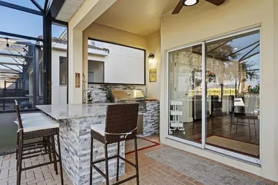 a kitchen with a bar with chairs and a large window at 6Q/4B | Piscina Privativa | Sala de Jogos Avengers in Orlando