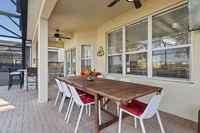 a dining room with a wooden table and white chairs at 6Q/4B | Piscina Privativa | Sala de Jogos Avengers in Orlando
