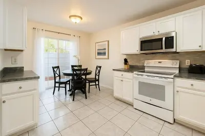 a kitchen with white cabinets and a table with chairs at 3Q/2B 15 min até a Disney, Piscina, Indian Wells in Kissimmee