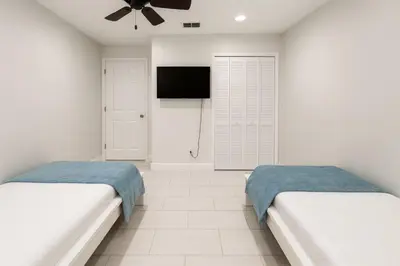 two beds in a white room with a flat screen tv at 3Q/2B Perto da DISNEY ☆ Piscina Priv. in Kissimmee