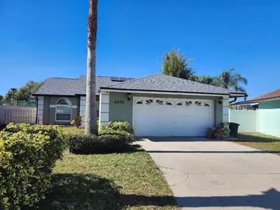 a house with a garage and a palm tree at 3Q/2B Perto da DISNEY ☆ Piscina Priv. in Kissimmee