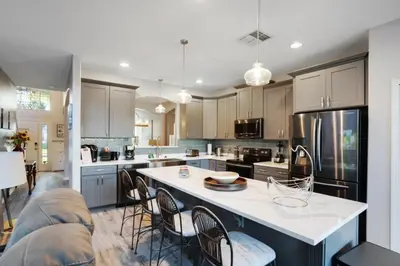 a kitchen with a large island with chairs in it at Six Bedroom Disney Home Lanai Screened Pool & Spa villa in Kissimmee
