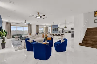 a large living room with blue chairs and a kitchen at Luxury Home - ALL the extras - Sleeps 39 in Kissimmee