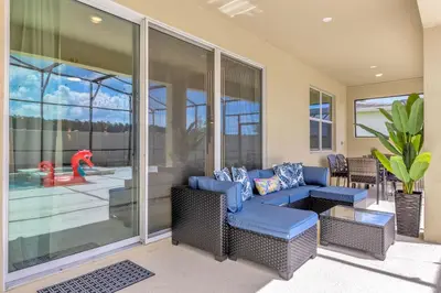 a living room with a blue couch and a patio at Luxury Home - ALL the extras - Sleeps 39 in Kissimmee