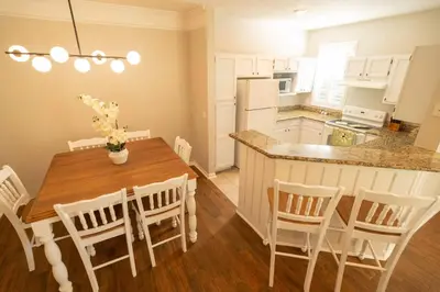 a kitchen with a wooden table and a kitchen with white appliances at Magical Themed 3BR Townhouse Near the Parks in Kissimmee