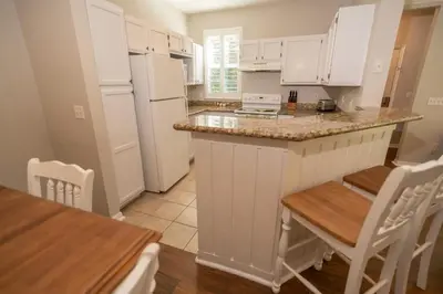 a kitchen with white cabinets and a table and chairs at Magical Themed 3BR Townhouse Near the Parks in Kissimmee