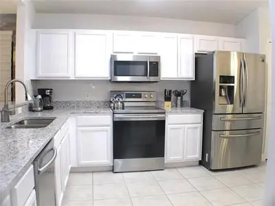 a kitchen with white cabinets and stainless steel appliances at Elegance House in Kissimmee