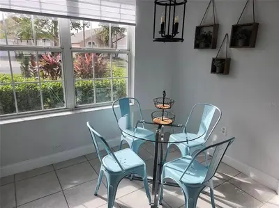 a dining room with a glass table and two blue chairs at Elegance House in Kissimmee
