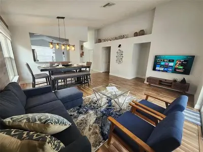 a living room with a blue couch and a dining room at Elegance House in Kissimmee
