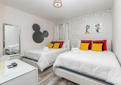 a bedroom with two beds and a mirror at Fantastic 5 BD Pool Near Disney Resort Perks in Kissimmee
