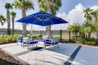 a table and chairs under a blue umbrella at Fantastic 5 BD Pool Near Disney Resort Perks in Kissimmee