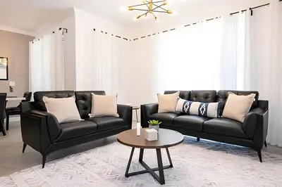 a living room with two black leather couches and a table at Villa Smile - 4Q/3B Storey Lake *Casa Luxuosa* in Kissimmee