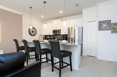 a kitchen with a table with chairs and a refrigerator at Villa Smile - 4Q/3B Storey Lake *Casa Luxuosa* in Kissimmee