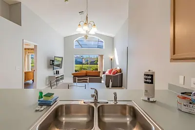 a kitchen with a sink and a living room at 4Q/2B Seu Refúgio Perto da Disney in Kissimmee