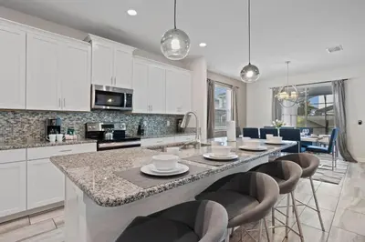 a kitchen with a large island with bar chairs at 4718 Sleepy Hollow Drive in Kissimmee