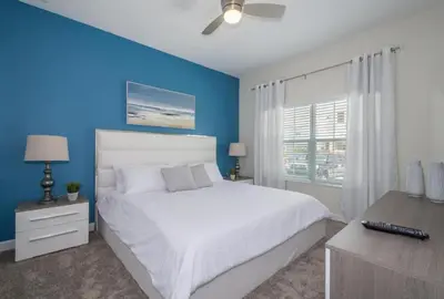 a bedroom with a white bed and a blue wall at 4 BD 3 BA Private Pool Storey Lake 4832 in Kissimmee
