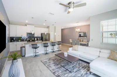 a living room with a white couch and a kitchen at 4 BD 3 BA Private Pool Storey Lake 4832 in Kissimmee