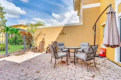 a patio with a table and chairs and an umbrella at Townhome 7 Mi to Disney Parks Resort Pool Access! in Kissimmee