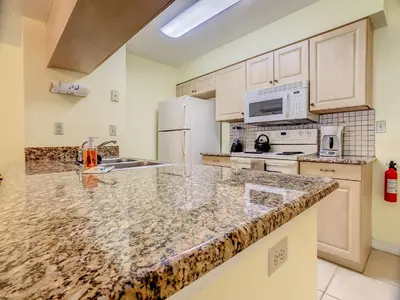 a kitchen with white appliances and a granite counter top at Quaint Getaway! 3 Bedroom Condo Near Disney Parks! in Kissimmee