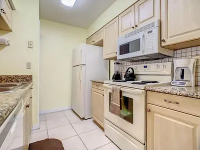 a kitchen with white appliances and white cabinets at Quaint Getaway! 3 Bedroom Condo Near Disney Parks! in Kissimmee