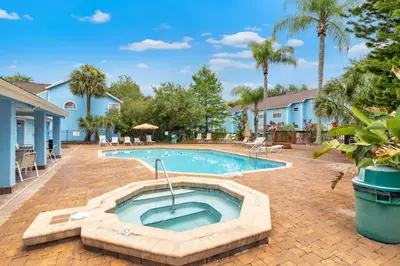 a swimming pool in the middle of a yard with palm trees at Quaint Getaway! 3 Bedroom Condo Near Disney Parks! in Kissimmee