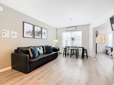 a living room with a black leather couch and a table at Be Our Guest! 1 Bedroom Condo Near Disney Parks! in Orlando