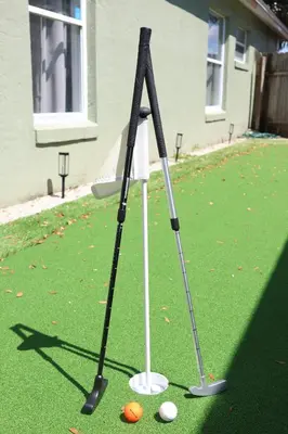 two golf clubs on a putting green with golf balls at Heated pool house with mini golf 10 min to Disney in Orlando