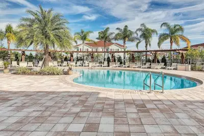 a swimming pool with palm trees in a resort at Disney World Charm Home 4BR and 3BA! in Kissimmee