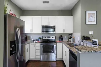 a kitchen with white cabinets and a stainless steel refrigerator at Disney World Charm Home 4BR and 3BA! in Kissimmee