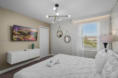 a white bedroom with a large white bed and a window at 2912 Storey Lake new game room 24 guests poolspa in Kissimmee