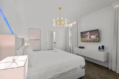 a white bedroom with a white bed and a chandelier at 2912 Storey Lake new game room 24 guests poolspa in Kissimmee