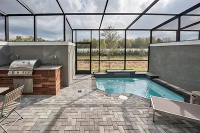 a swimming pool in a glass house with a grill at Family and Fun Home with Splash Pool at Le Reve 08 in Kissimmee