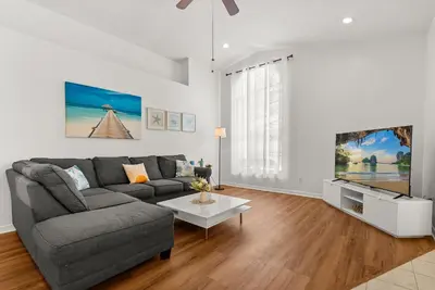 a living room with a gray couch and a tv at 3 Quartos + Piscina e Game Room em Orlando in Kissimmee
