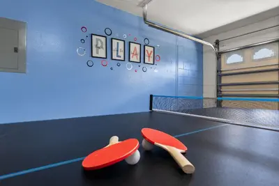 two ping pong paddles sitting on a ping pong court at 3 Quartos + Piscina e Game Room em Orlando in Kissimmee