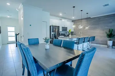 a kitchen and dining room with a table and blue chairs at Townhouse c/Piscina Priv. Perto da Disney in Kissimmee