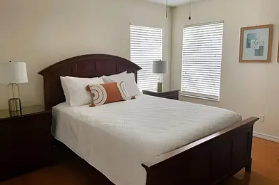 a bedroom with a large bed with white sheets and pillows at 6Q/5.5B Luxo Piscina Priv. Disney in Kissimmee